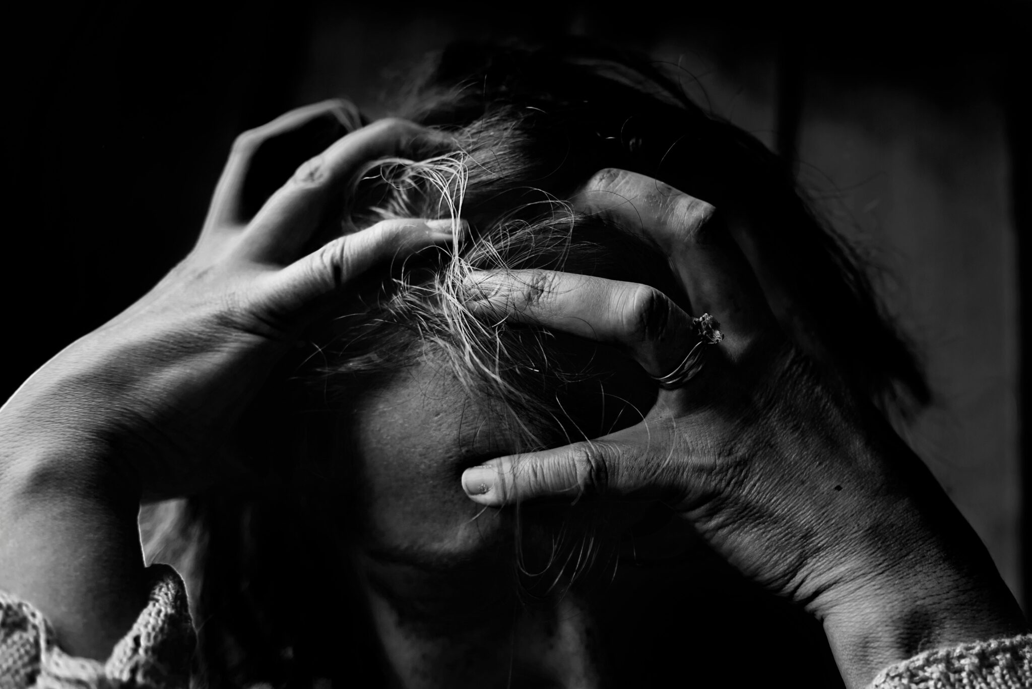 Женщина смотрит в окно в раздумьях, чувствуя сомнение в себе и тревогу